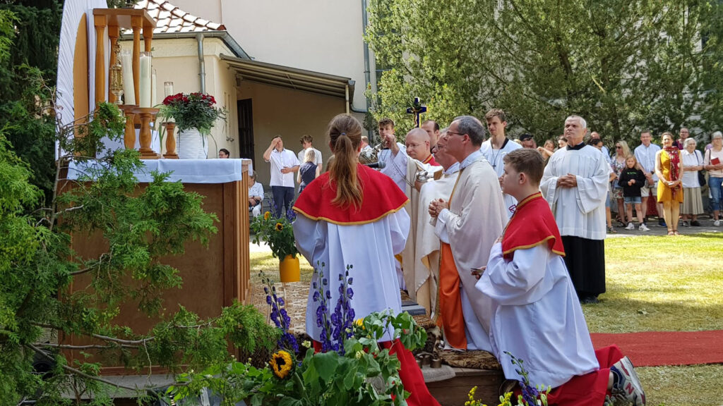 Priester und Ministranten knien am Außenaltar, die Gemeinde versammelt sich herum