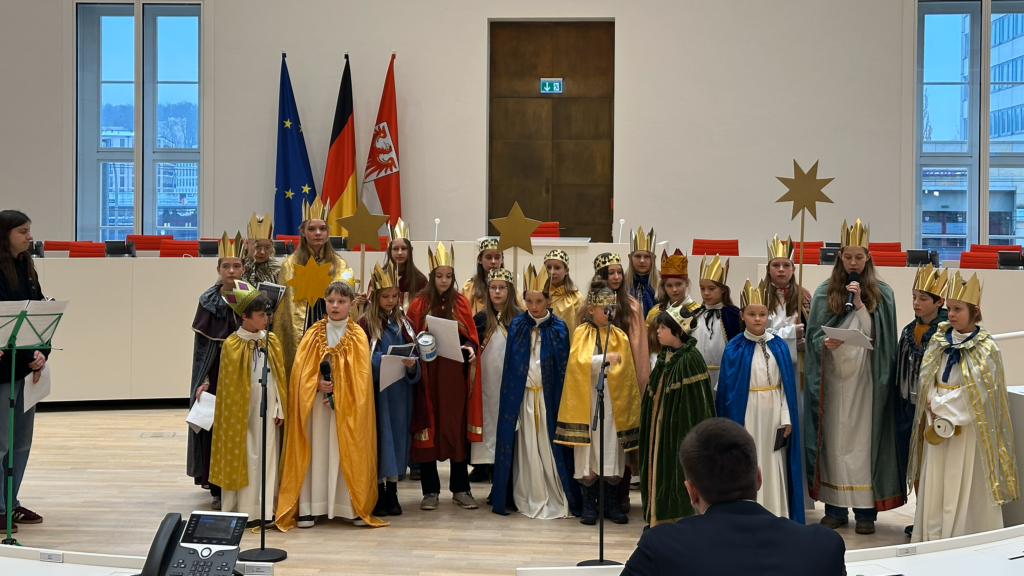 Sternsingergruppe im Plenarsaal, im Hintergrud Flaggen