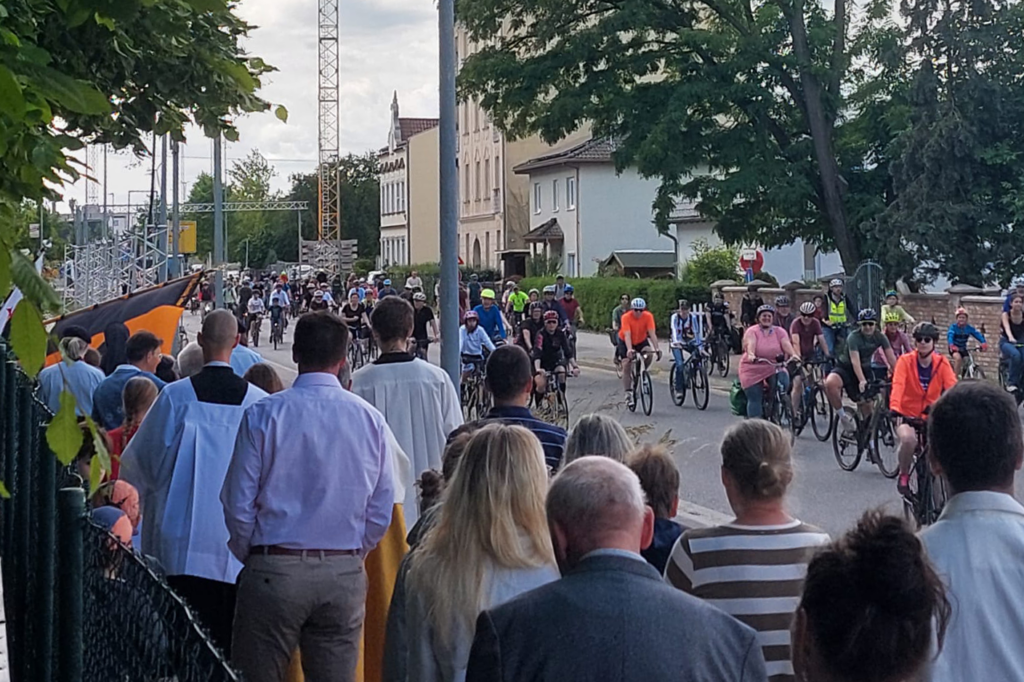 Die Prozession vieler Gemeindemitglieder trifft an der Straße auf die Radfahrer der ADFC-Sternfahrt